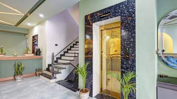 Un hall d’hôtel comprenant un comptoir d’accueil, un escalier et une entrée au rez-de-chaussée.