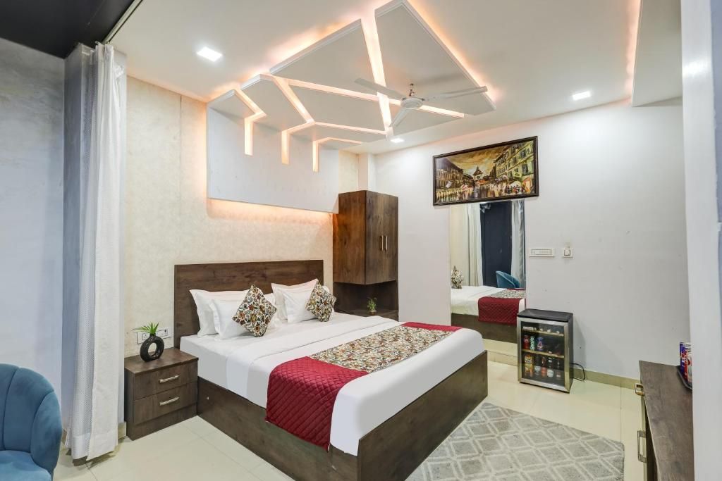 Un dormitorio moderno con una cama grande, un ventilador de techo, un televisor montado en la pared y un mueble auxiliar.