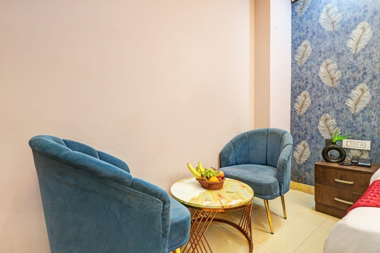 Una habitación con dos sillones azules, una mesita redonda con una cesta de frutas y un aparador con una radio.