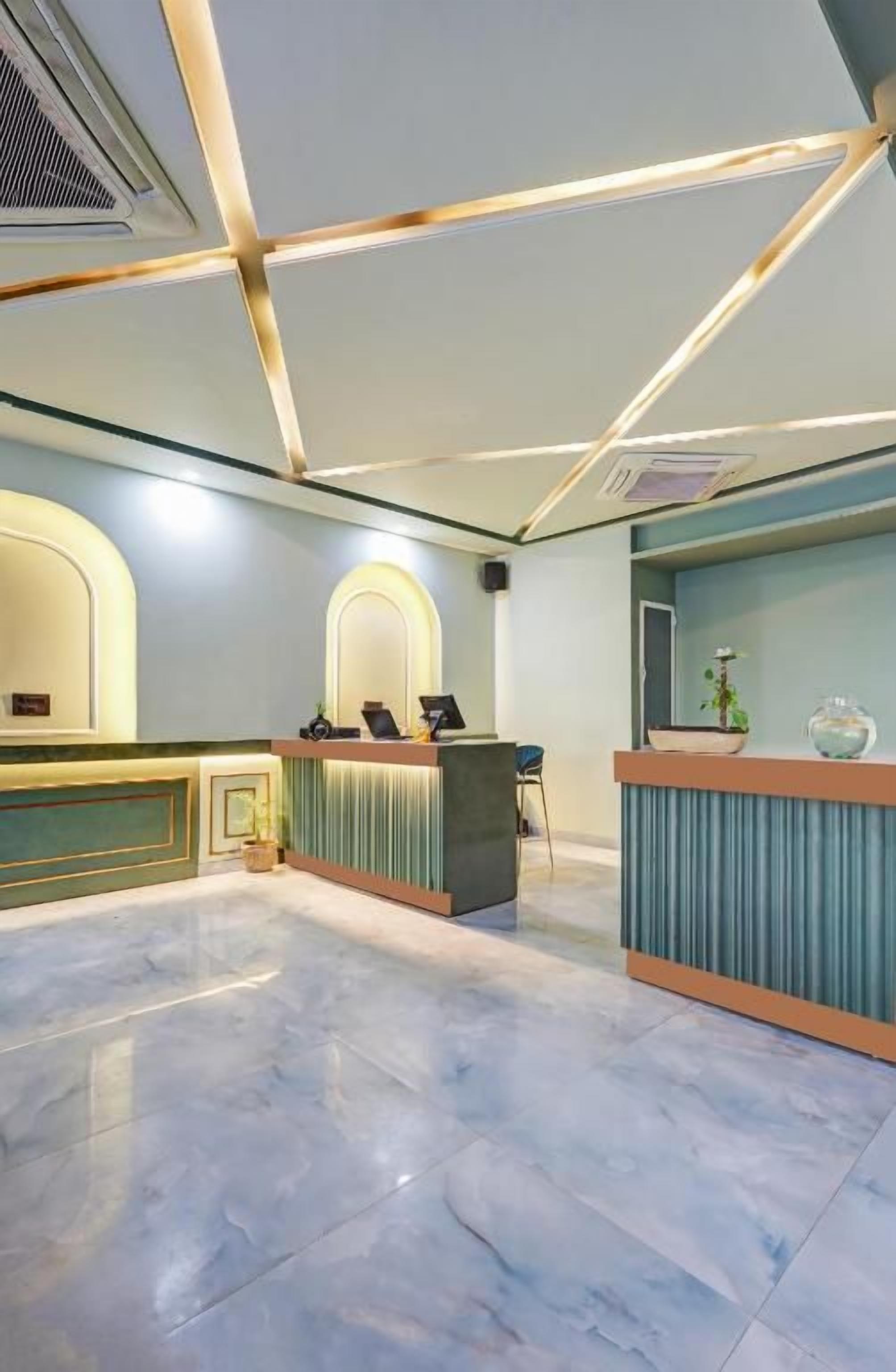 Un vestíbulo de hotel con mostrador de recepción, zona de estar y techo decorativo.