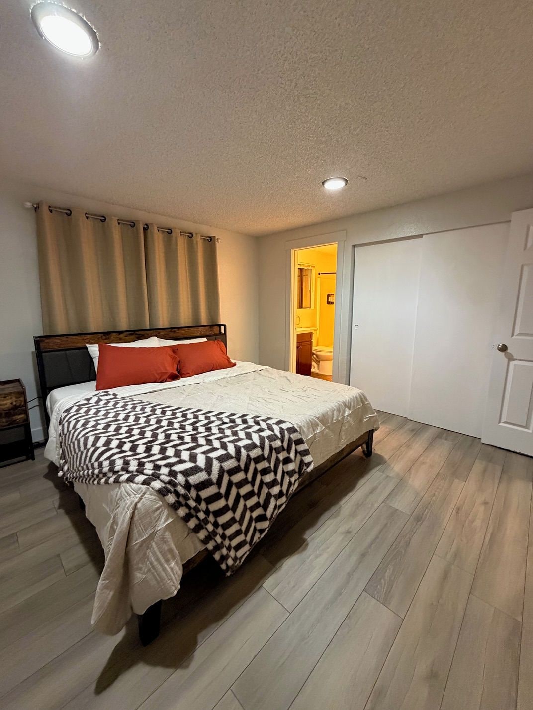 Une chambre à coucher avec un lit, des rideaux, une porte et un luminaire.