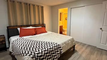 A bedroom with a bed, curtains, a door, and a light fixture.