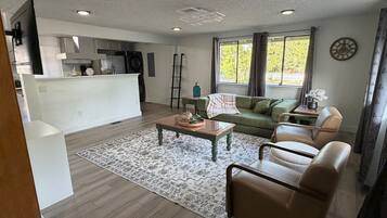 A modern living room with a sofa, coffee table, and a view of the kitchen.