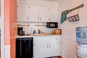A compact kitchen with white cabinets, a microwave, and a water dispenser.