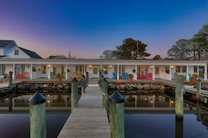 A waterfront property with a dock leading to a house with multiple windows and outdoor seating.