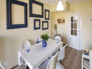 A dining area with a white table, chairs, and a vase of green plants. - Holiday Home in Cabo de Palos With Views (Cartagena)