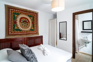Ein Hotelzimmer mit einem Bett, einer großen Wandteppich, einem Spiegel und einem Badezimmer mit Waschbecken.
