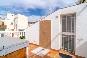 Ein Balkon mit weißer Decke, einer braunen Tür und einem Fenster mit Metallgitter.