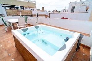 Eine Dachterrasse mit Whirlpool, Sitzgelegenheiten im Freien und Blick auf die Stadtlandschaft.