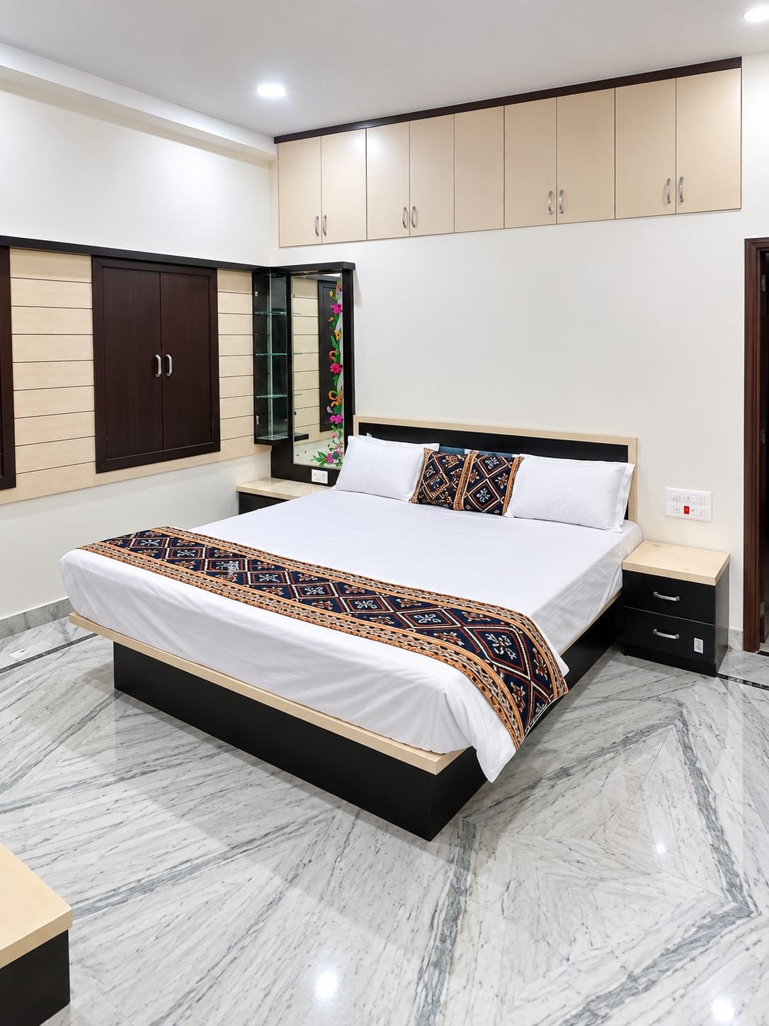 A bedroom with a large bed, a nightstand, a wardrobe, and a mirror.