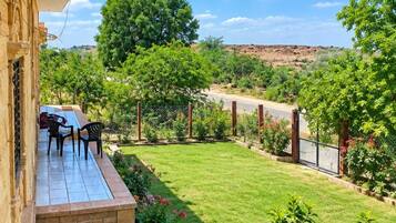 A patio with outdoor seating, a well-maintained lawn, and a view of a hilly landscape.