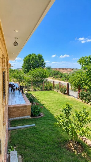 Un patio con mobiliario exterior, un césped cuidado y vistas a un paisaje montañoso.
