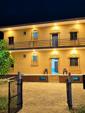 A two-story building with a balcony, a door, and a gate.