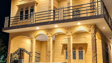A two-story building with ornate architectural details, a balcony, and a gated entrance.