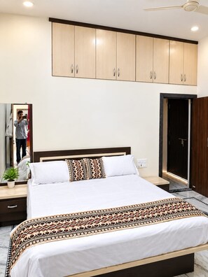 Un dormitorio con cama, mesita de noche, espejo y armario.