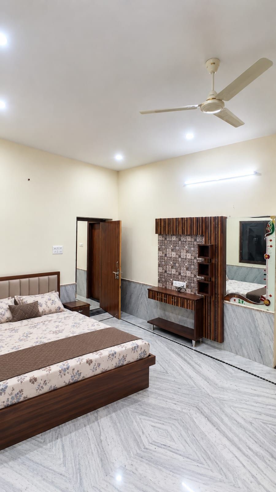 A bedroom with a bed, a ceiling fan, a built-in TV, and a wardrobe.