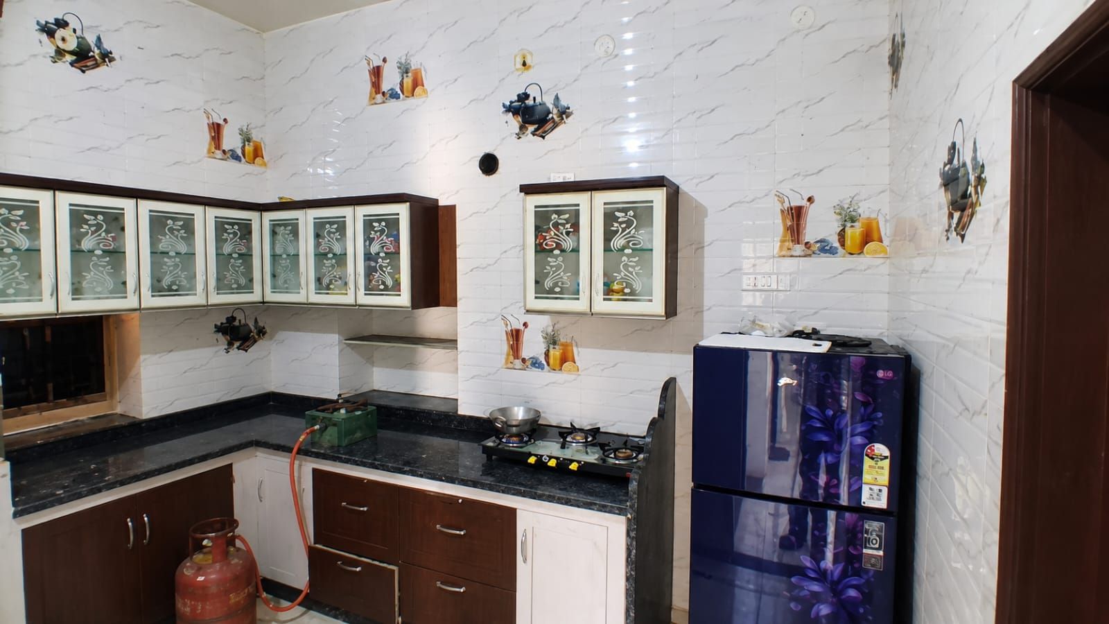 A kitchen with white marble backsplash, wooden cabinets, and a blue refrigerator.