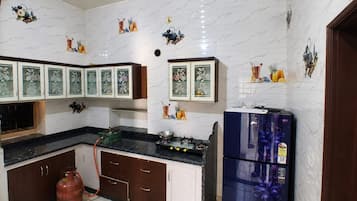 A kitchen with white marble backsplash, wooden cabinets, and a blue refrigerator.