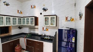 Una cocina con salpicadero de mármol blanco, armarios de madera y un refrigerador azul.