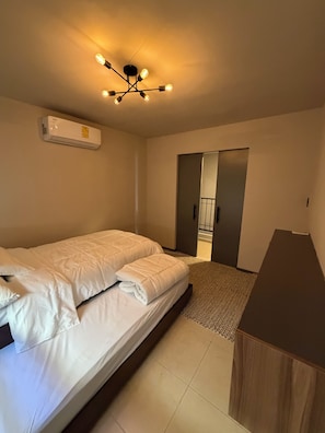A bedroom with a bed, a desk, and a ceiling light fixture.