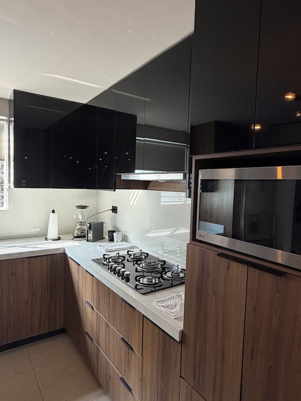 A modern kitchen with dark cabinets, a stainless steel stove, and a microwave.