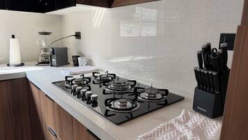 Cozinha moderna com fogão a gás, cafeteira e suporte para facas.