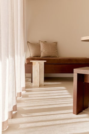 Una habitación con un banco de madera, una mesita redonda y un suelo de tonos claros.