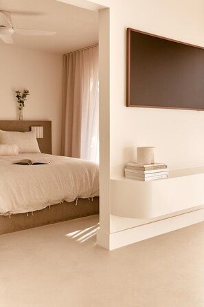 A minimalist bedroom with a bed, a bedside table with books, a vase with flowers, and a large mirror on the wall. - Contemporary 1B Apt - 900m to Hastings St (Noosa Heads)