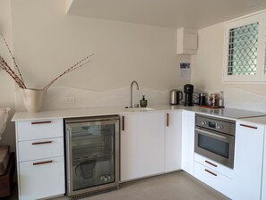 Eine moderne Küche mit weißen Schränken, einem eingebauten Kühlschrank, einer Kaffeemaschine und einem Backofen.