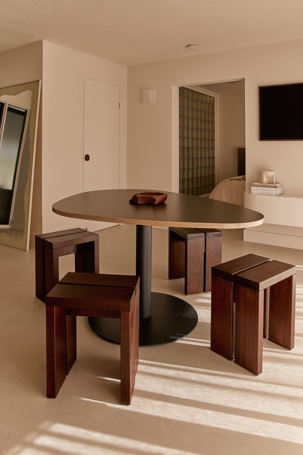 A modern dining area with a round table, wooden stools, and a minimalist design.