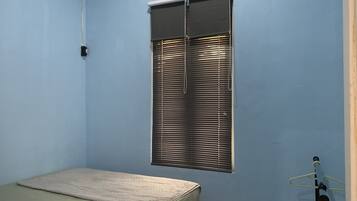 Ein Zimmer mit einem Bett, einem Fenster mit Jalousien und einer Tür mit Handtuchhalter.