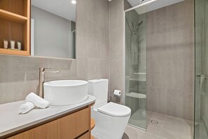 Un baño moderno con lavamanos, inodoro y cabina de ducha de vidrio.