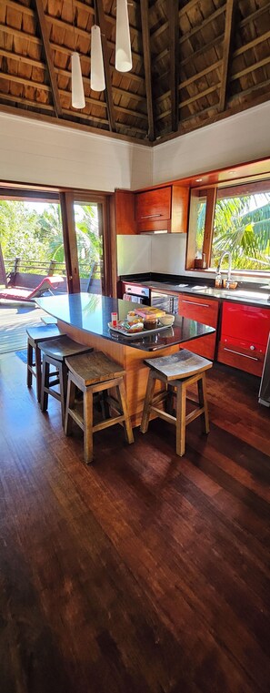 A spacious kitchen with a large island, wooden stools, and a red appliance. - Moorea Villa with Hot Tub & Outdoor Bath – Walk to Pool, Tennis & Gym (Moorea-Maiao)