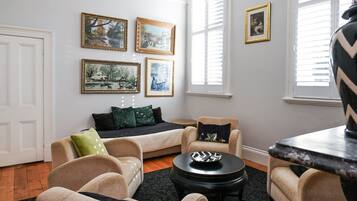 A living room with a sofa, armchairs, a coffee table, and framed artwork on the walls.