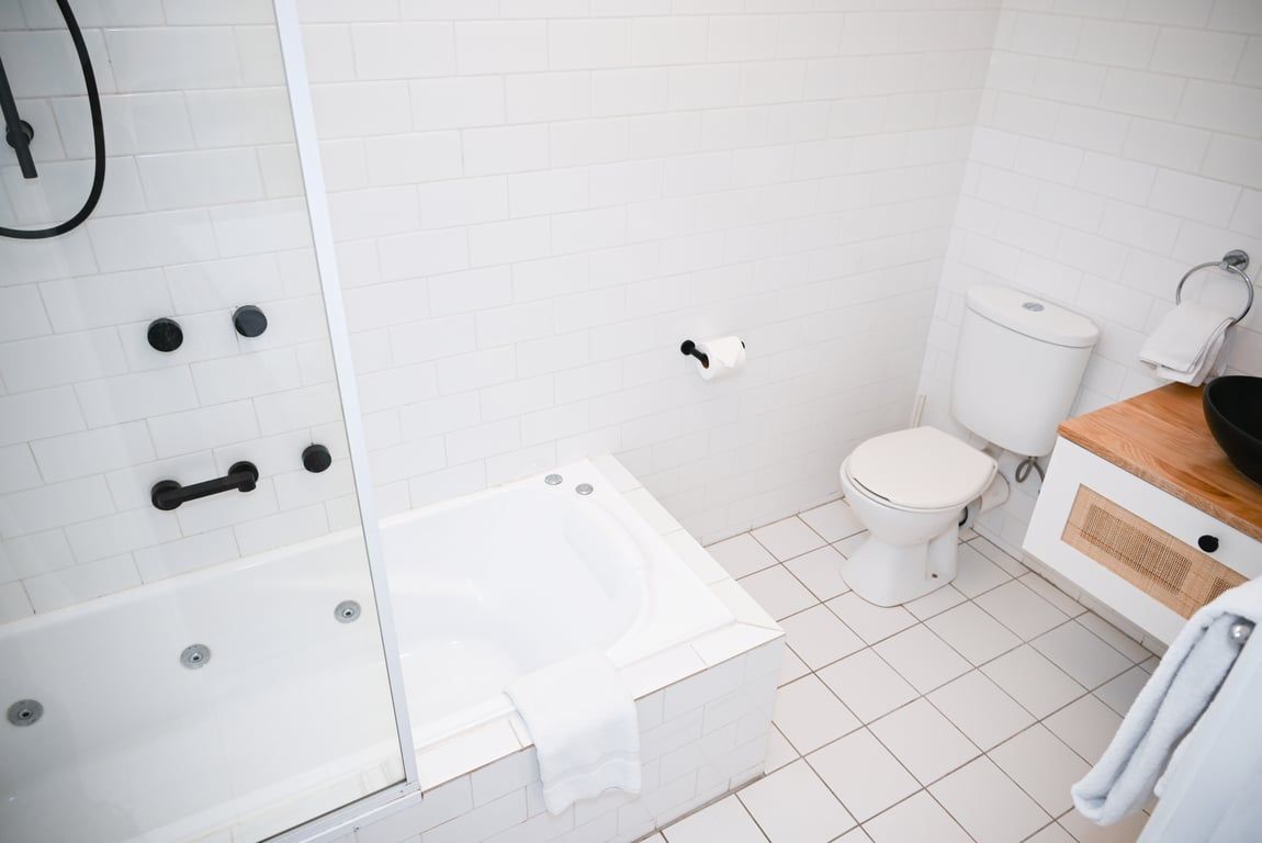 A bathroom with a white bathtub, toilet, and a shower area.
