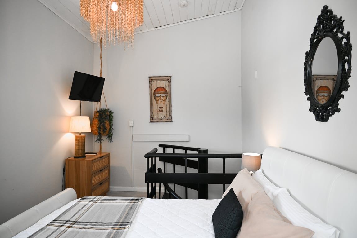 Una camera da letto con un letto, una TV, una scrivania e uno specchio.