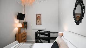 Una camera da letto con un letto, una TV, una scrivania e uno specchio.