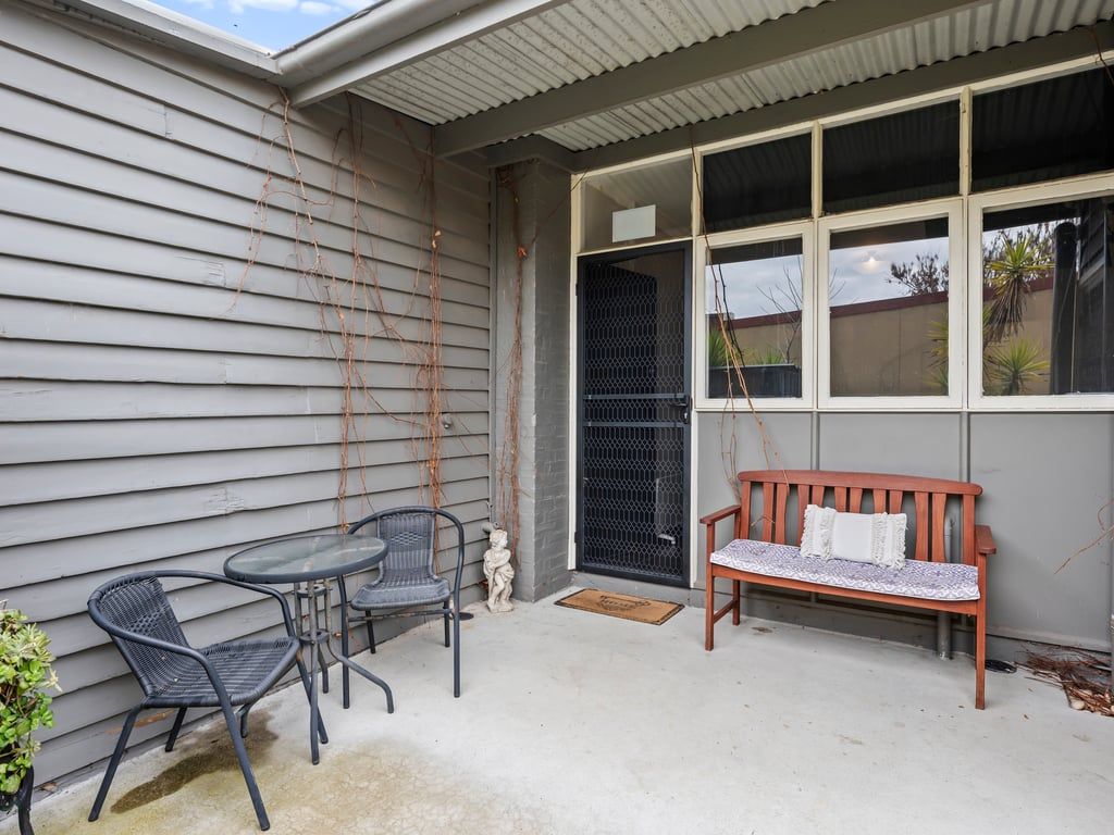 A patio with two chairs, a bench, and a small statue.