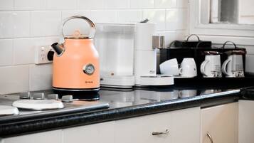 A kitchen with a kettle, coffee maker, and a coffee station.