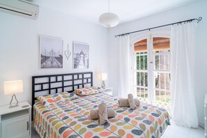 A bedroom with a bed, two bedside tables, a window with curtains, and two wall-mounted pictures. - Villa in Nerja Near Burriana Beach (Nerja)