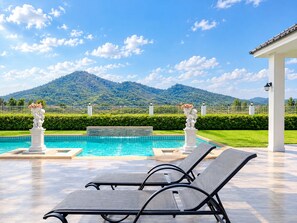 Ein Poolbereich mit Liegestühlen, einer Springbrunnen und Blick auf einen Berg.