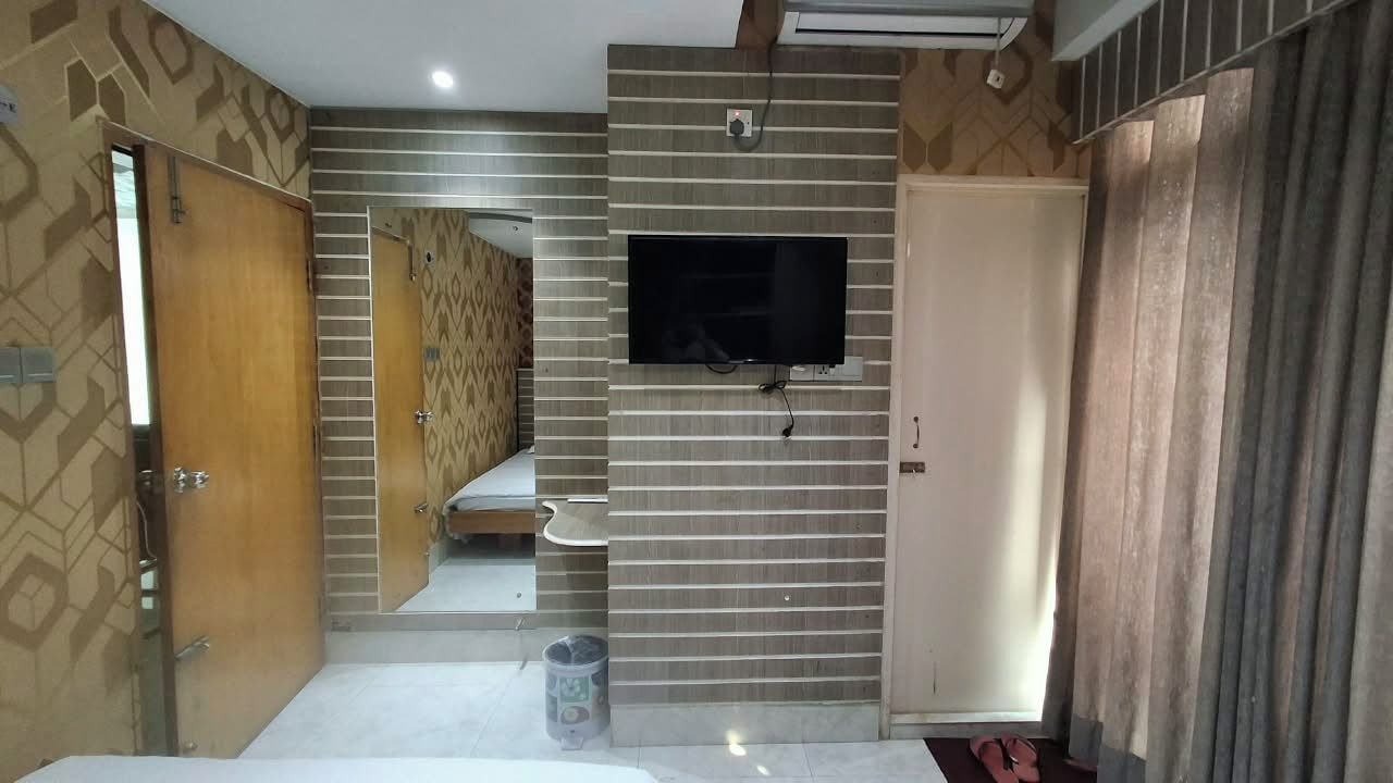 A bathroom with a mirror, a toilet, a sink, and a television mounted on the wall.