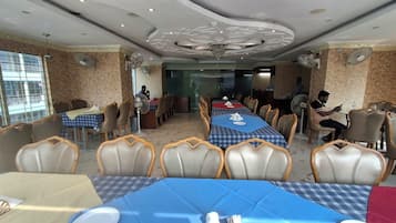 A dining area with tables set for multiple people, chairs, ceiling fans, and a chandelier.