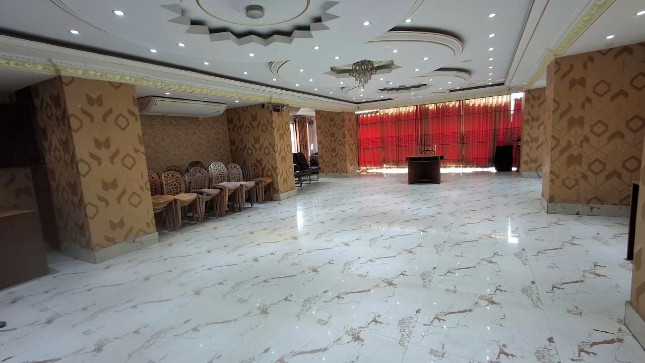 Un amplio salón con suelo de mármol, paredes decoradas y un escenario con un atril.