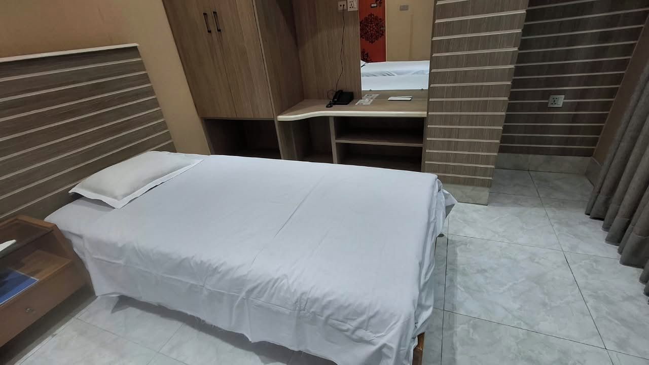 A hotel room with a bed, a desk, and a wardrobe.