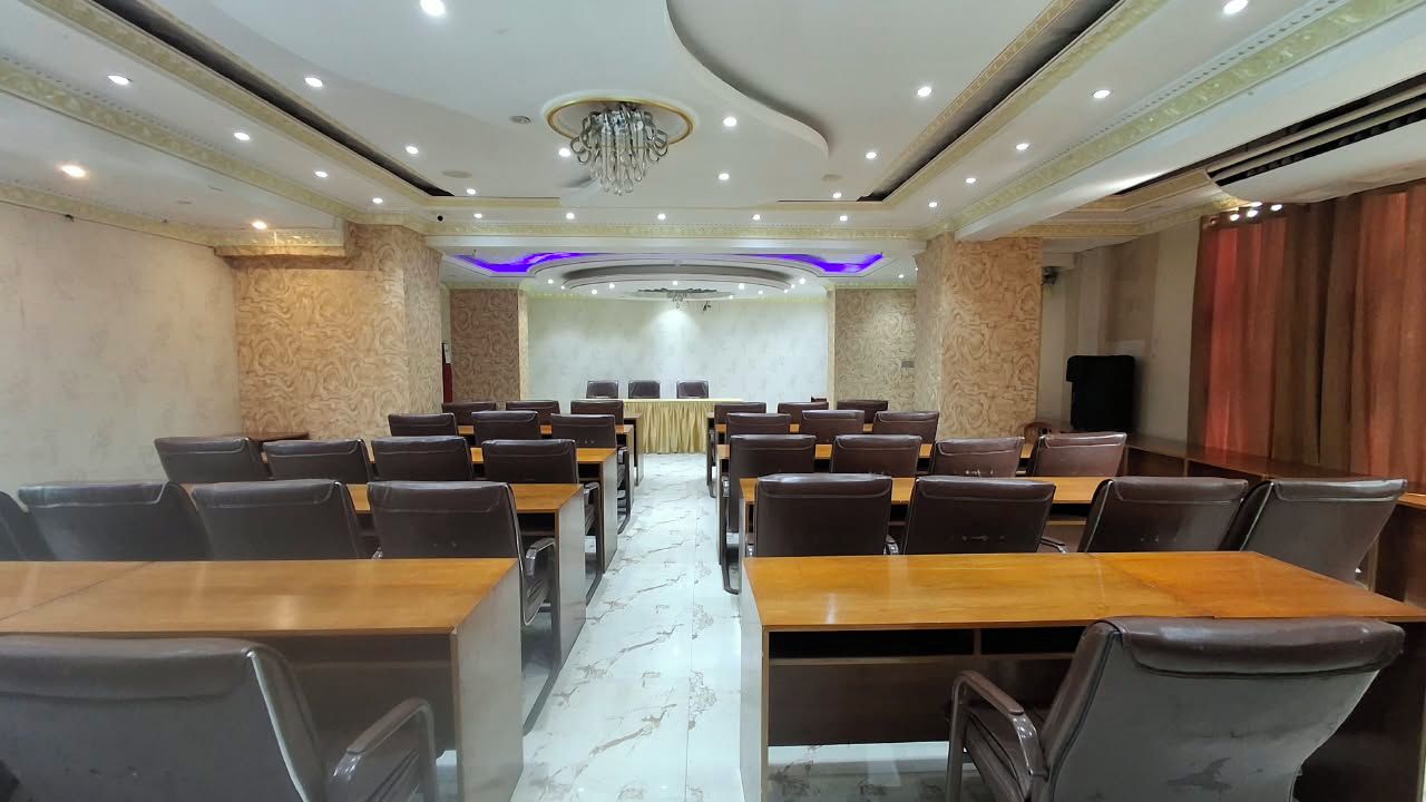 A conference room with a long table and multiple chairs, a chandelier, and patterned walls.