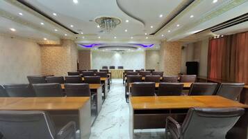 A conference room with a long table and multiple chairs, a chandelier, and patterned walls.