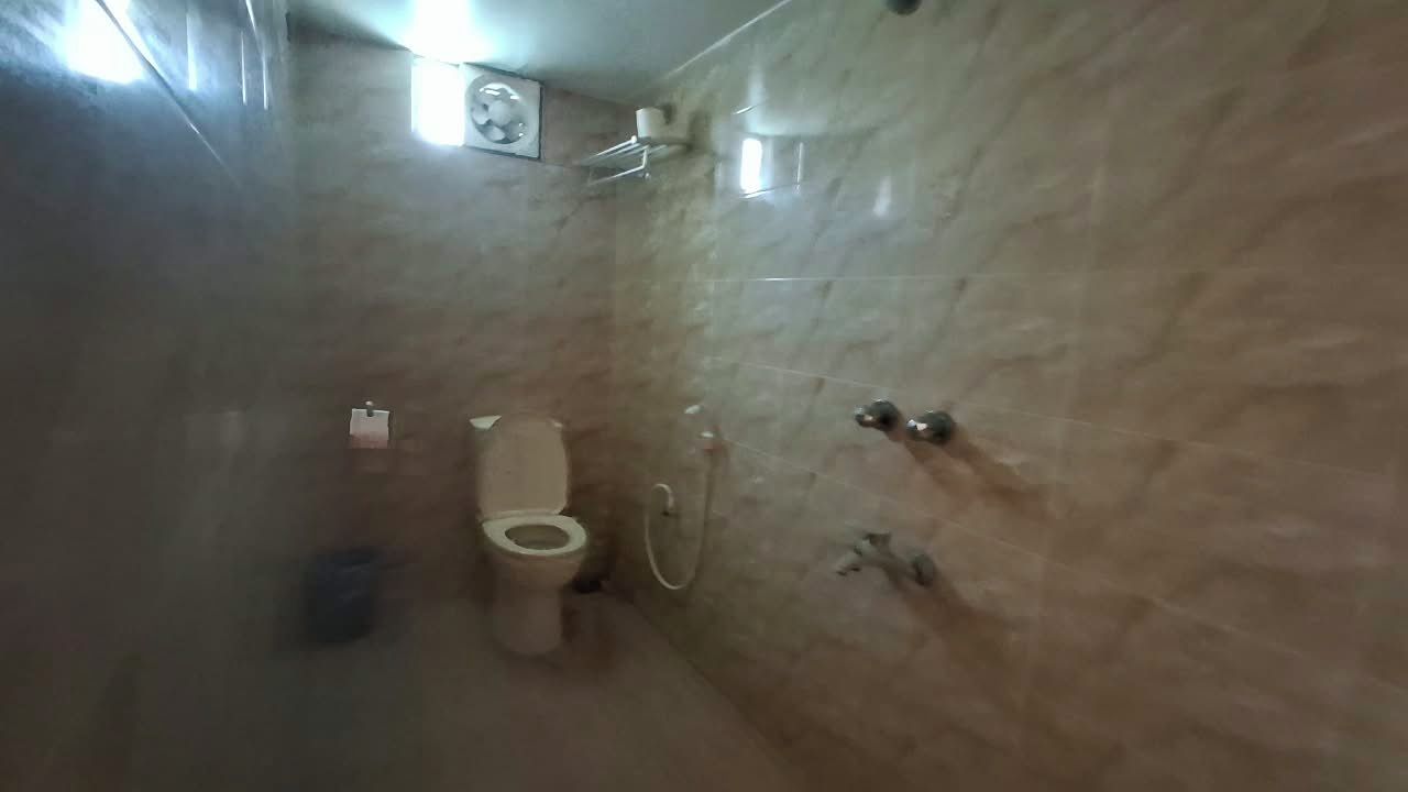 A bathroom with a toilet, a shower, and a marble wall.