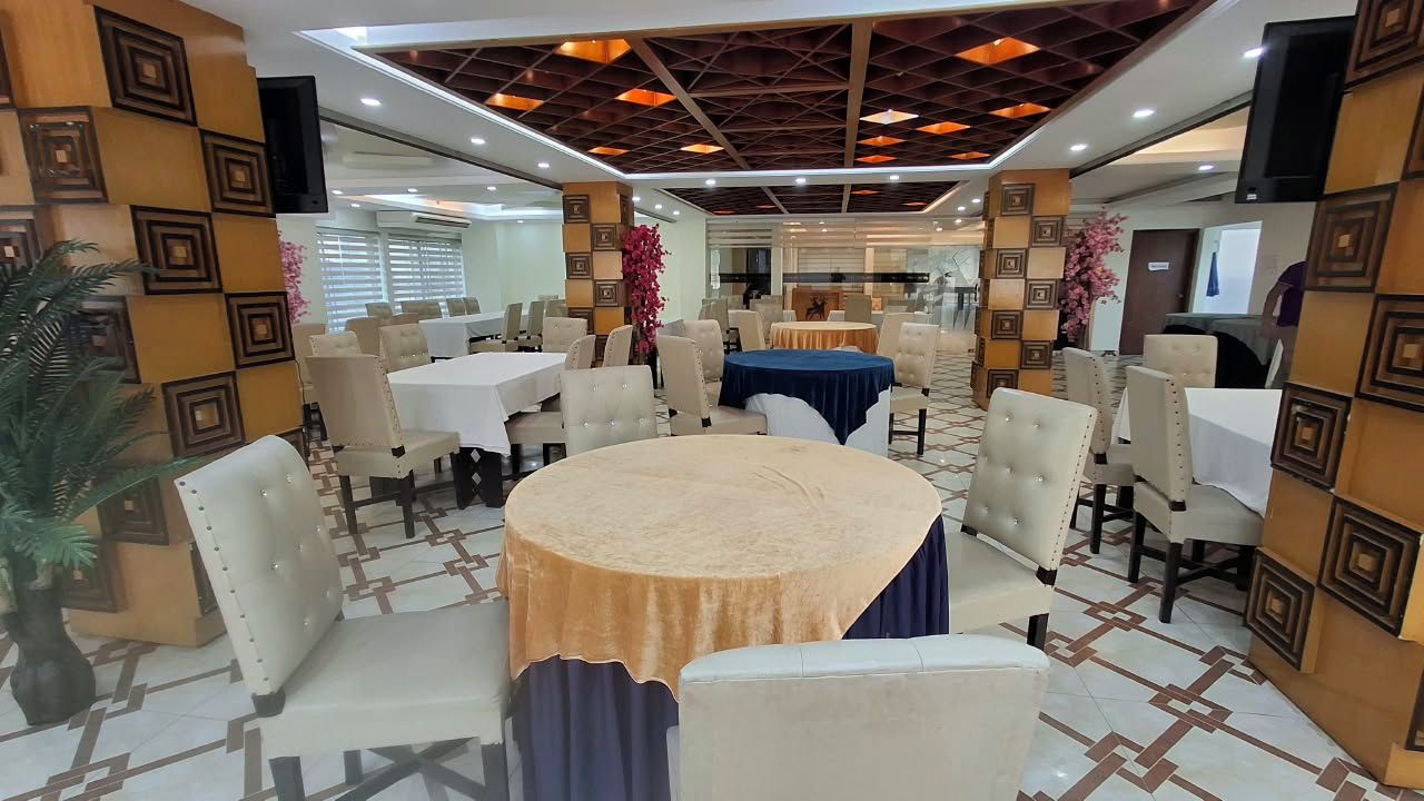 A conference room with round tables, chairs, and a stage area.