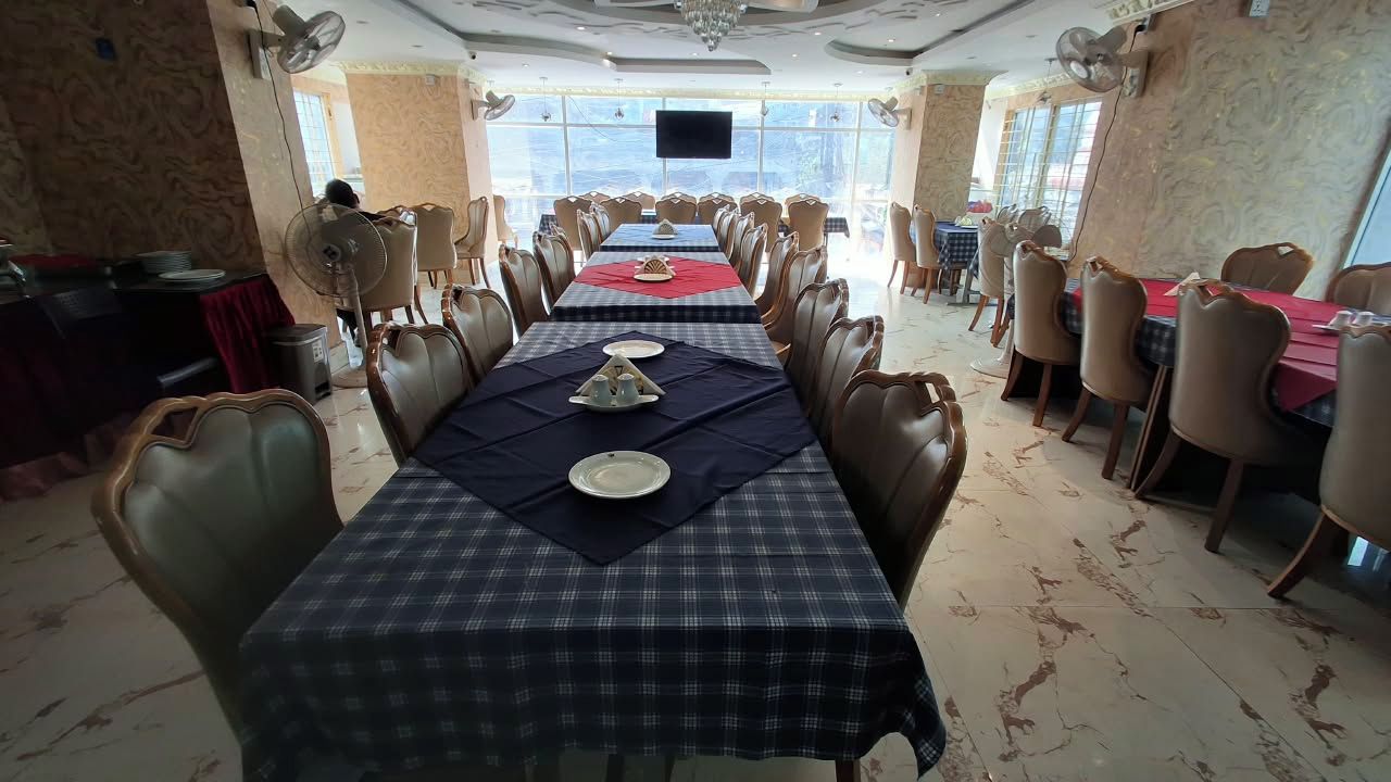 Un comedor con varias mesas, sillas y una pantalla de televisión montada en la pared.